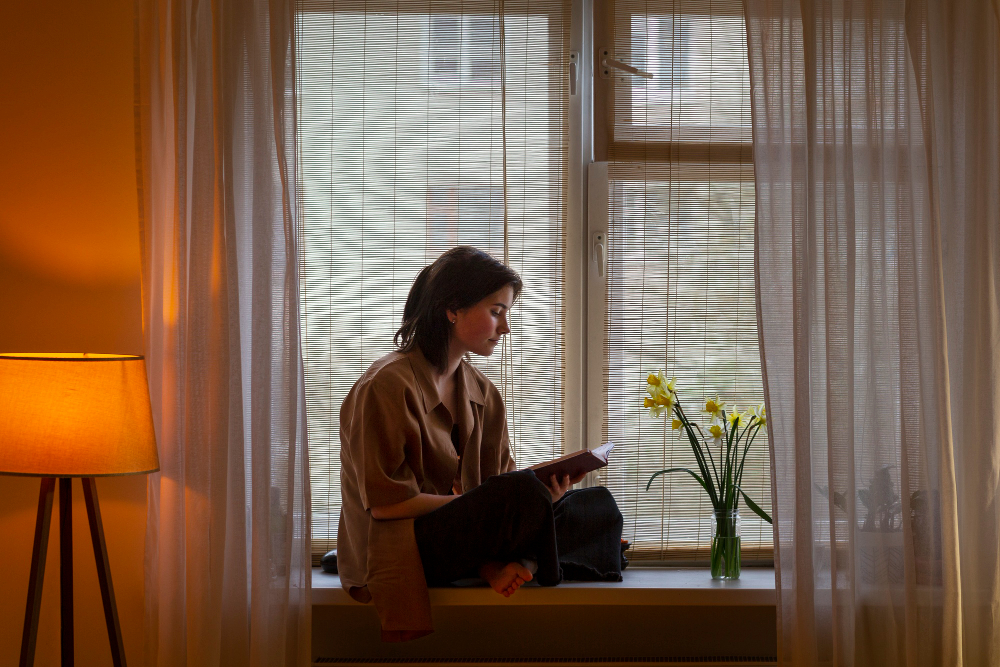 Lady reading a book at her windowstill with beautiful window treatments